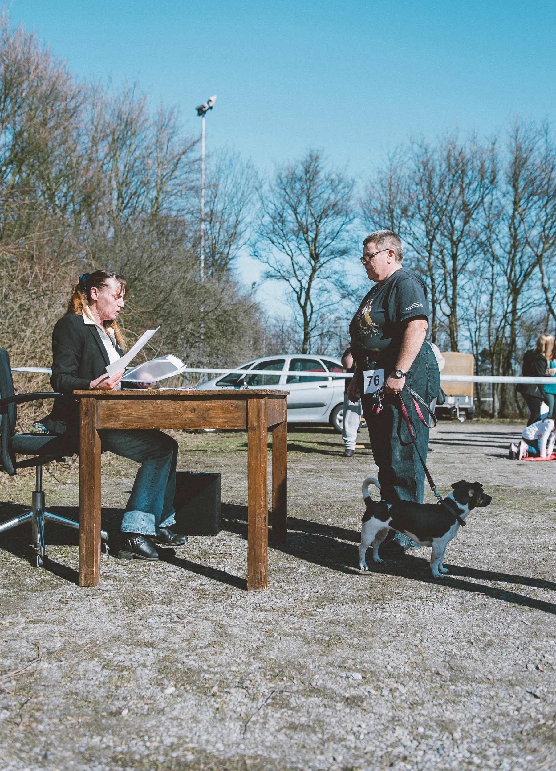 Participant and dog registering at a wooden desk outdoors.